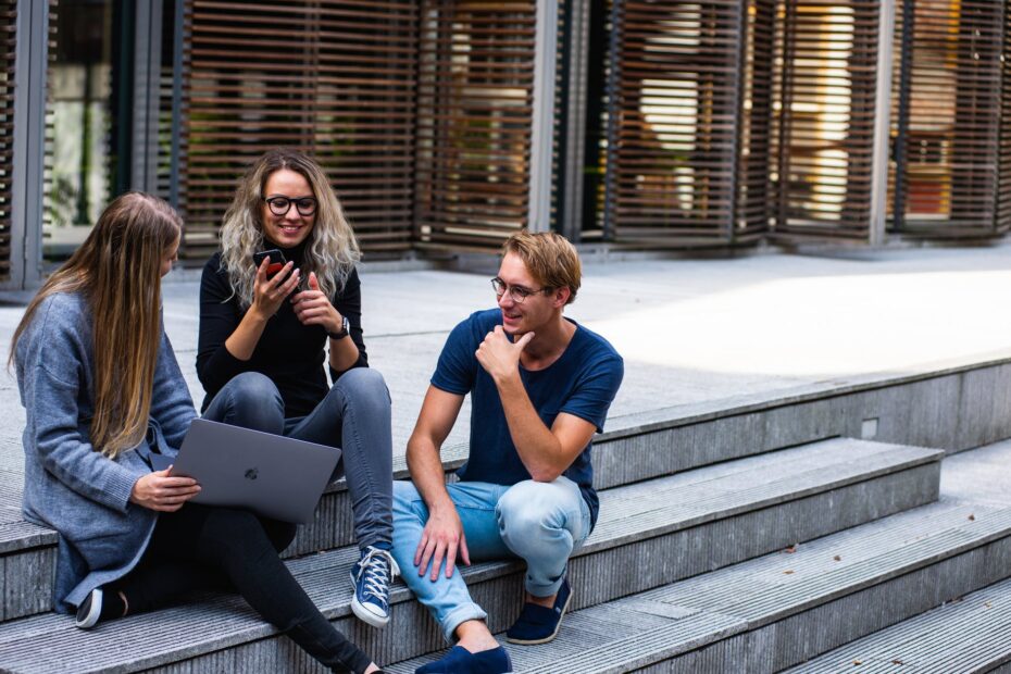 three persons sitting on the stairs talking with each other