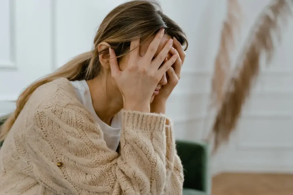 An image of a domestic abuse survivor with her head in her hands